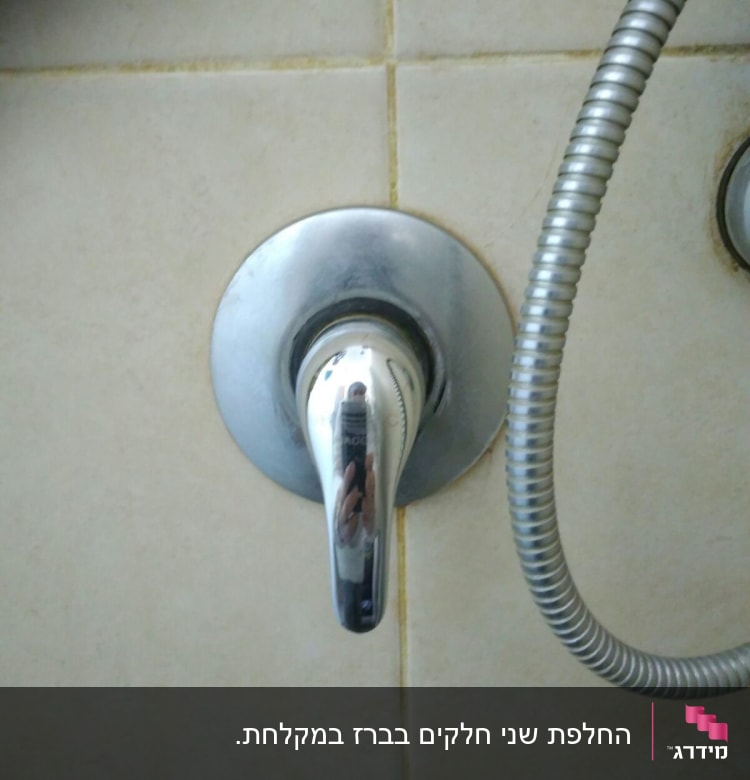 ברז כרום עם צינור מתכת על קיר אריחים